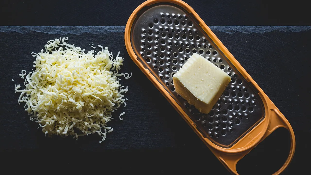 Pote de vidro com frango desfiado úmido e dourado, ao lado de garfo usado para desfiar
