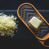 Pote de vidro com frango desfiado úmido e dourado, ao lado de garfo usado para desfiar
