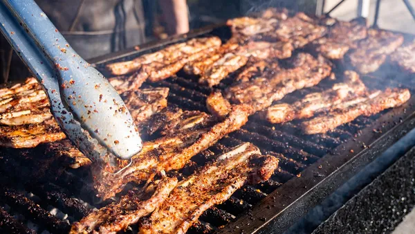 Costela bovina assada no bafo desmanchando, exibindo o osso solto e a carne fibrosa e suculenta sobre tábua de madeira
